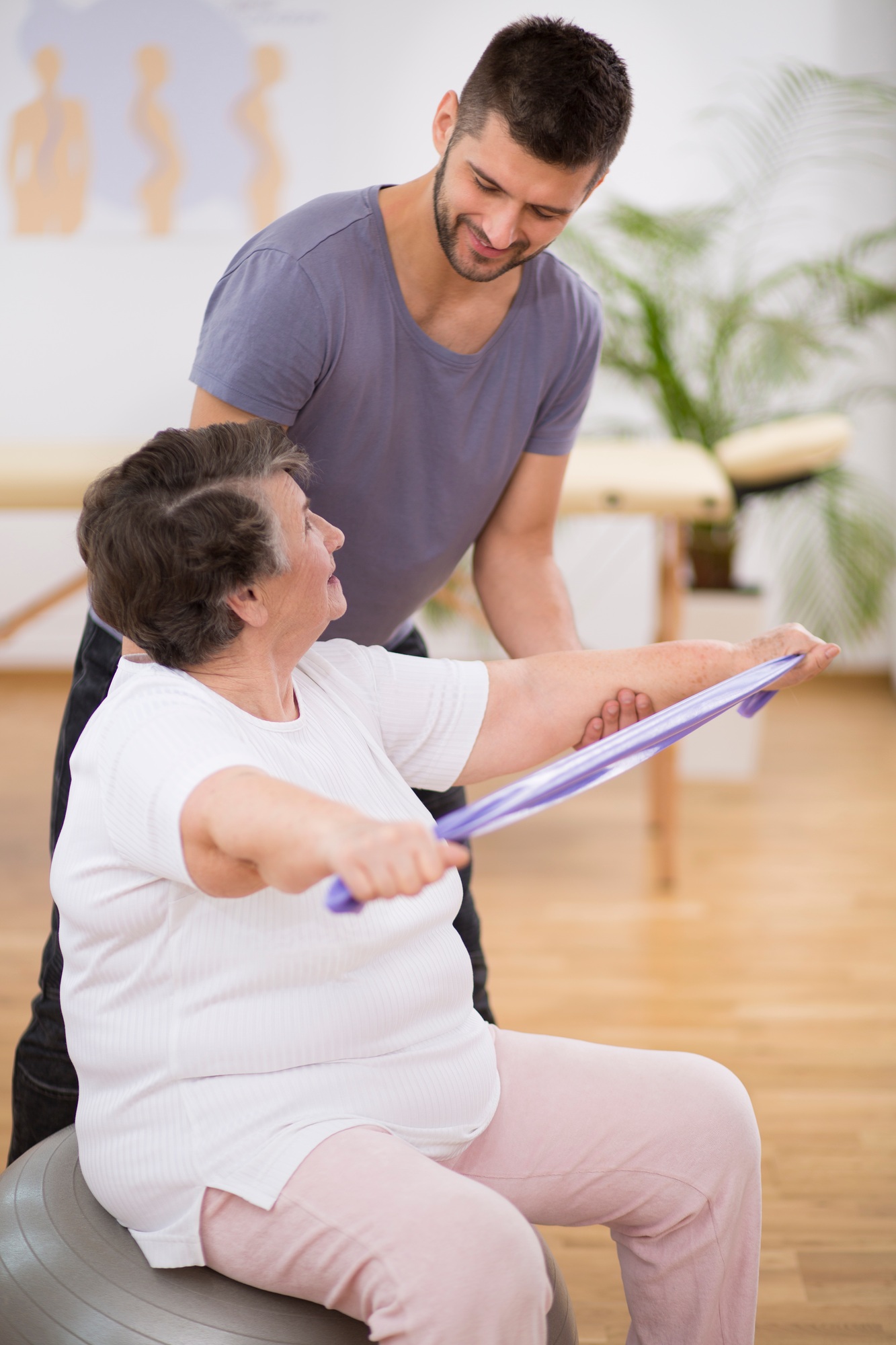 Elderly pensioner exercising with resistance bands with her professional physiotherapist