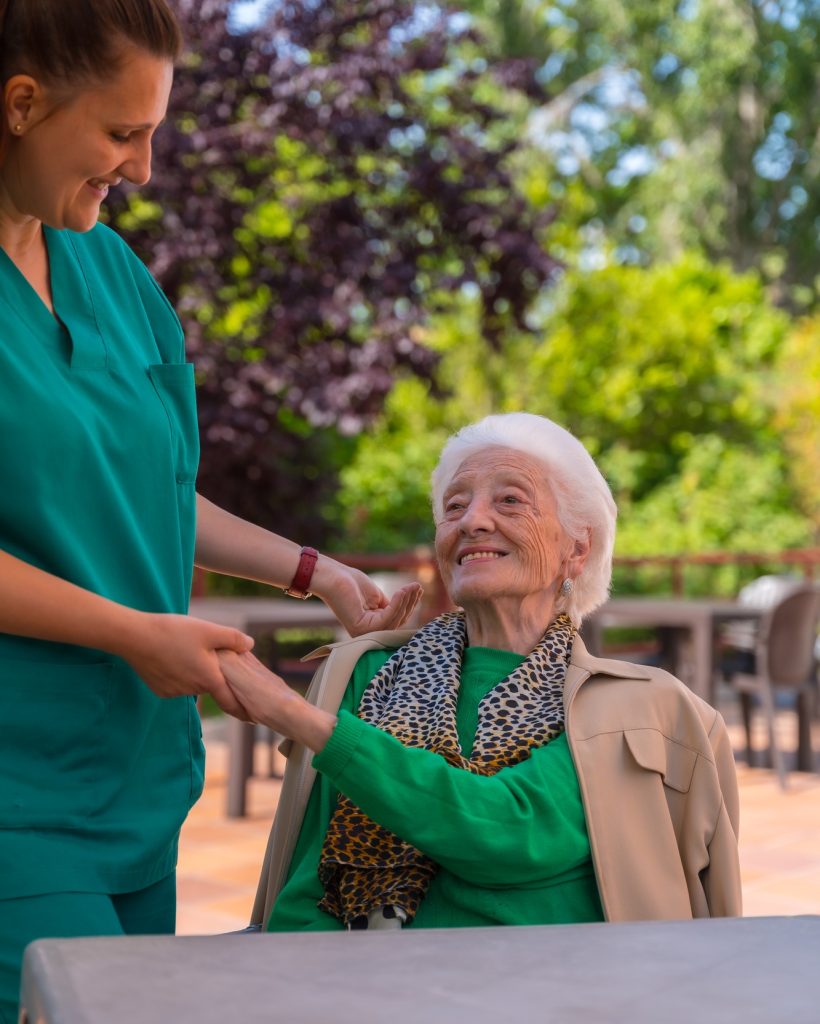 An older or mature woman with the nurse in the garden of a nursing home in a moment